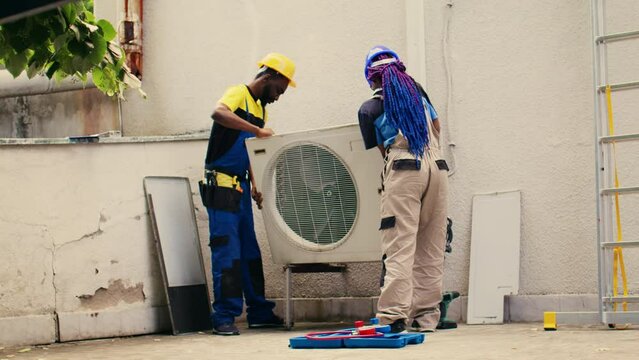 Licensed expert commissioned by client to work on out of order air conditioner, dismantling condenser metal coil panel. Precise wireman opening hvac system to check for bad wiring