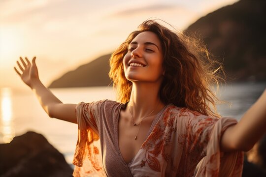Backlit Portrait of calm happy smiling free woman with open arms and closed eyes enjoys a beautiful moment life on the seashore at sunset 