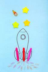 Creative composition with drawn rocket and different stationery on blue background