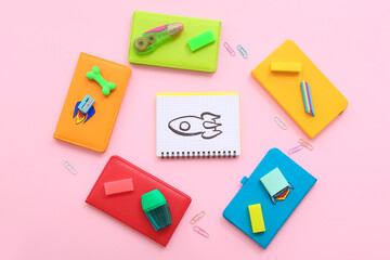 Creative composition with drawn, paper rockets and different stationery on pink background