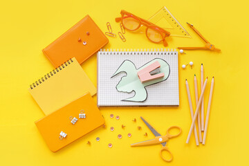 Creative composition with paper rocket and different stationery on yellow background