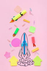 Creative composition with drawn rocket and different stationery on pink background
