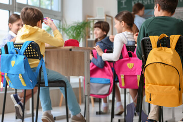 Little pupils with backpacks having lesson in classroom, back view