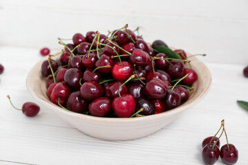 Naklejka na ściany i meble Bowl with sweet cherries on white wooden background