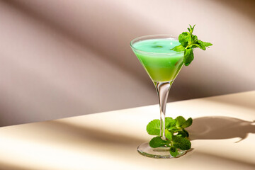 Grasshopper cocktail, green alcoholic drink with mint liqueur, cream, ice and fresh mint. Beige background, hard light, shadow pattern, copy space