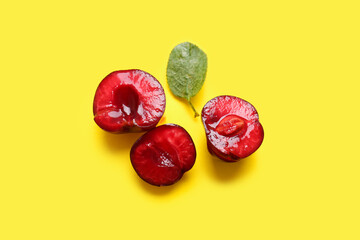 Halves of sweet cherries and leaf on yellow background
