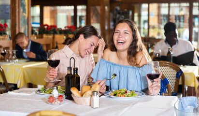 Women lesbian lgbt couple enjoying dinner with wine and having conversation at restaurant