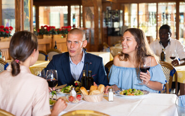 Group of friends dining together at restaurant, laughing, talking and having fun