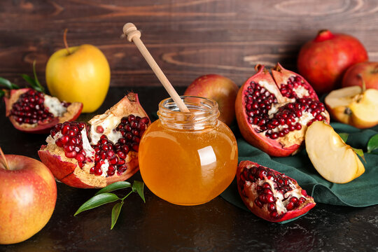 Jar of honey, pomegranate and apples for Rosh Hashanah celebration (Jewish New Year) on black table