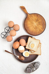 Plate and holder with boiled chicken eggs on white background