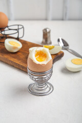 Holder with boiled chicken egg on white background