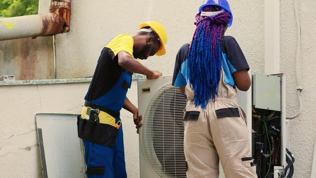 Seasoned mechanic and adept repairman opening up old broken hvac system to replace it with new performant external air conditioner, after draining freon and replacing ductwork.