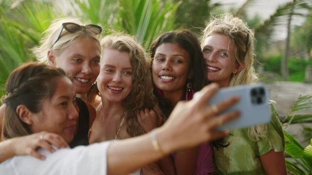 Cheerful multiracial girls take selfies on vacation. Diverse young women taking self portraits with smartphone. Multiethnic happy female friends taking photos smiling and laughing on exotic location
