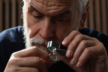 Professional jeweler working with ring on dark background, closeup