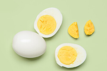 Tasty boiled egg with halves on green background
