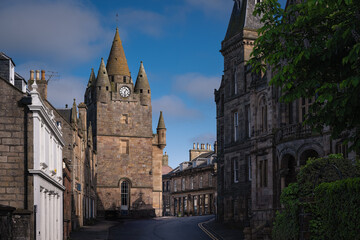 Fototapeta premium 2023-06-04 MAIN STREET THROUGH CITY OF TAIN WITH OLD STONE BUILDINGS WITH SPIRLAS AND A CLOCK IN SCOTLAND