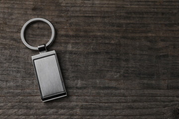 Metallic keychain on wooden background, top view. Space for text