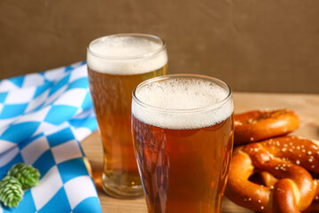 Flag of Bavaria, mugs with beer and pretzels on wooden table, closeup