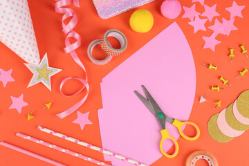 Different stationery and materials for creation of colorful party hats on orange background, flat lay. Handmade decorations
