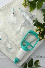 Cupping therapy. Plastic cups, hand pump, towels and hypericum perforatum berries on white wooden...