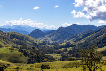 Obraz premium Panorama of mountainous terrain with forest and small houses. Panoramic view of vast expanses of mountain ranges and large ranges on the horizon. Immense distances of wavy relief. Rio de Janeiro