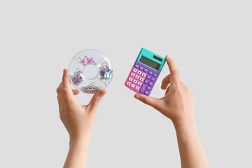 Female hands holding case with stationery and calculator on grey background