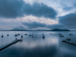 Fototapeta premium Foggy sunrise over the water with boats