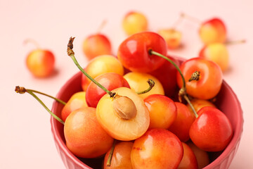 Bowl with sweet yellow cherries on pink background