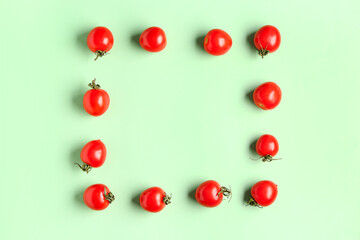 Frame made of fresh cherry tomatoes on green background