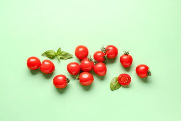 Naklejka na ściany i meble Fresh cherry tomatoes and basil on green background