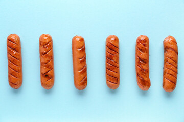 Tasty grilled sausages on blue background