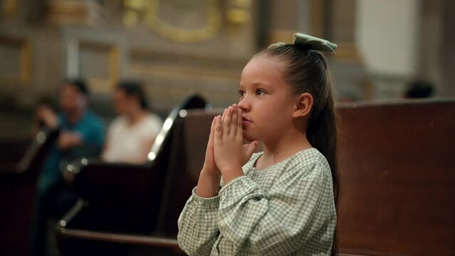 Ni&ntilde;a concentrada hermosa rubia latina hispana rezando meditando orando con sus manos juntas hincada de rodillas pidiendo en el templo iglesia parroquia bas&iacute;lica santuario 