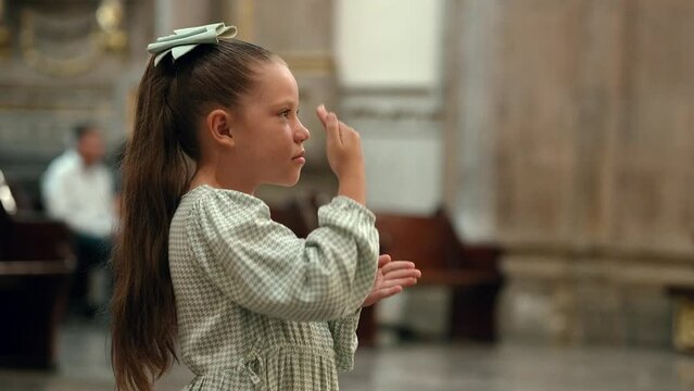Ni&ntilde;a hermosa rubia latina hispana rezando meditando orando con sus manos juntas hincada de rodillas pidiendo en el templo iglesia parroquia bas&iacute;lica santuario persignando 