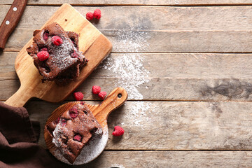 Boards with pieces of raspberry chocolate brownie on wooden table