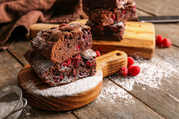 Board with pieces of raspberry chocolate brownie on wooden table
