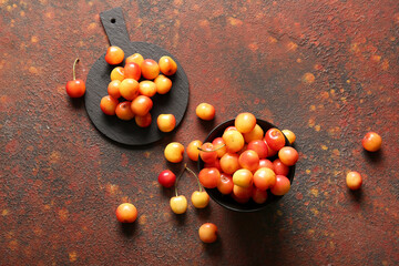 Bowl and board with sweet yellow cherries on dark table