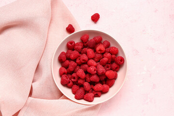 Bowl with fresh raspberries on pink background