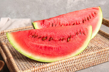 Wicker tray with pieces of fresh watermelon on grey table