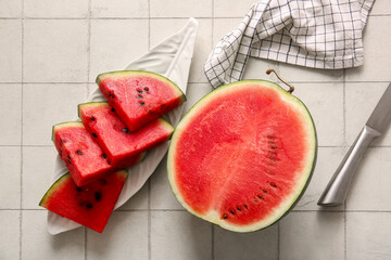 Half of fresh watermelon and plate with pieces on white tile table