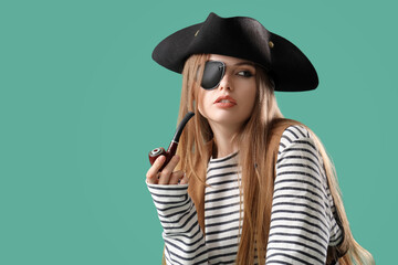 Beautiful female pirate smoking pipe on green background
