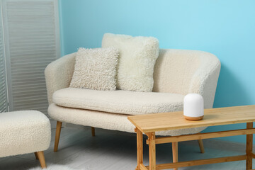 Cozy white sofa, table and ottoman near blue wall