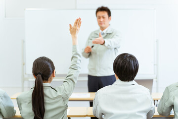 Fototapeta na wymiar 会議室で講習・セミナーを受ける挙手をして質問する女性の後ろ姿 