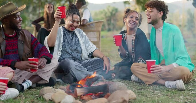 Friends camping at music festival with drinks, fire and happiness, freedom and fun at outdoor event. Nature, camp and group of people picnic at campfire, happy young men and women relax together.
