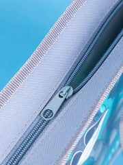 close-up of a zipper on a gray school pencil case on a blue background. Back to school. copy space
