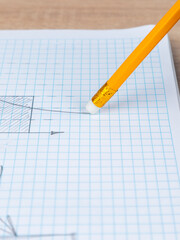Close-up woman erasing a graph with a white  rubber band on a slate pencil in a checkered notebook
