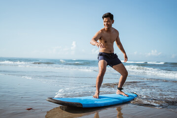 a man practicing surfing by standing on a surfboard on the sand at the beach