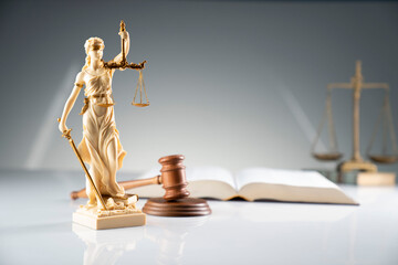 The law concept background.  White statue of Themis, gavel, scale and legal code on the white table.