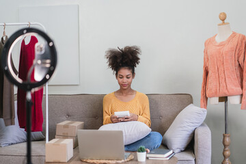 African american fashion merchant woman use calculator and selling online clothes in live streaming