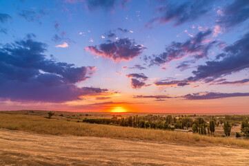 Bright amazing warm summer sunset over the hills. Lilac sunset sky.