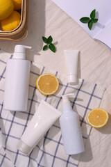 Several types of cosmetic container decorated on a checkered fabric with a basket of lemons. Empty label for cosmetic product mockup of Lemon (Citrus limon) extract